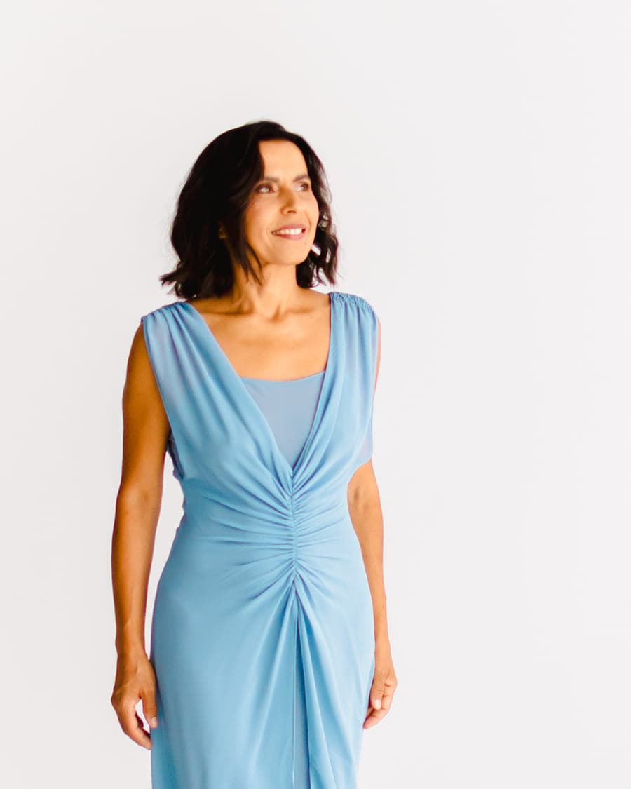 Sónia Brito de vestido azul-claro, a sorrir e a olhar para o lado.
