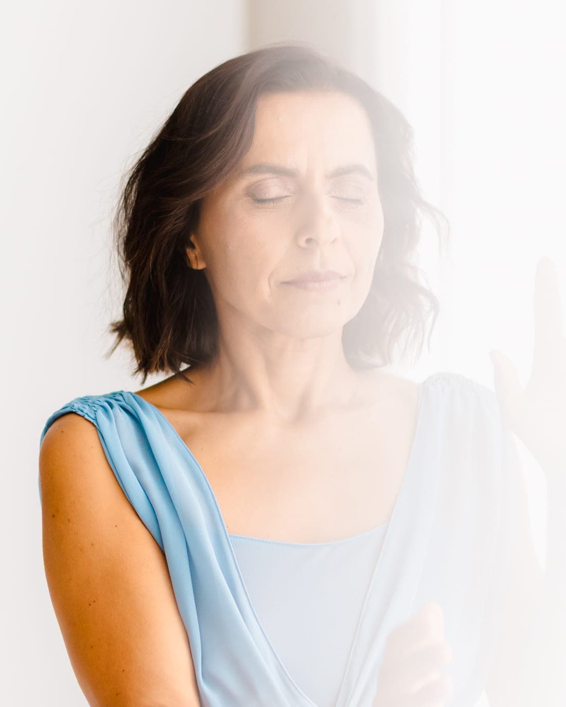 Sónia Brito de olhos fechados, com um véu de luz sobre o rosto e os ombros.
